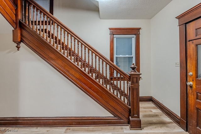 stairs featuring a textured ceiling and hardwood / wood-style flooring