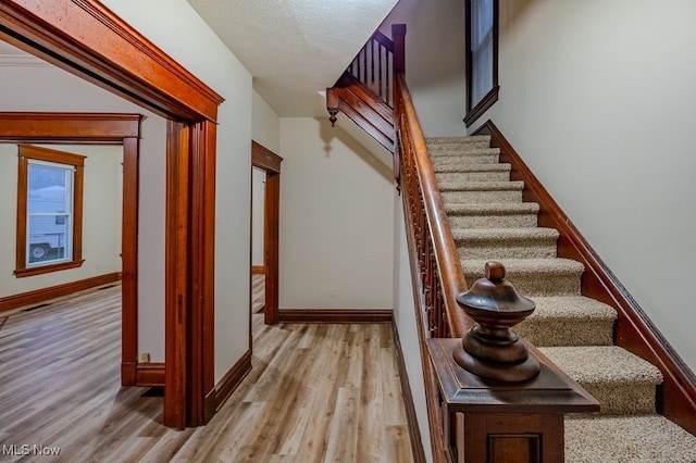 staircase featuring hardwood / wood-style floors and a textured ceiling