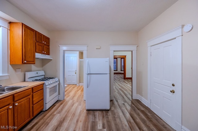 kitchen with white appliances, light hardwood / wood-style flooring, and sink