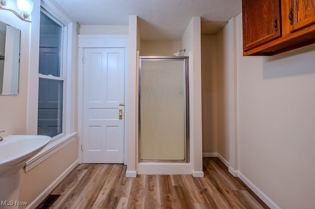 bathroom with wood-type flooring and a shower with door