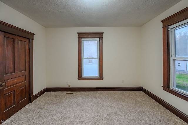 carpeted empty room with a textured ceiling