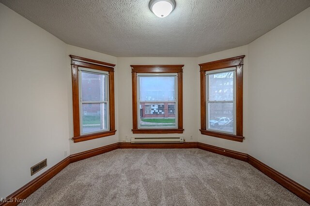 carpeted spare room with a textured ceiling and a baseboard radiator