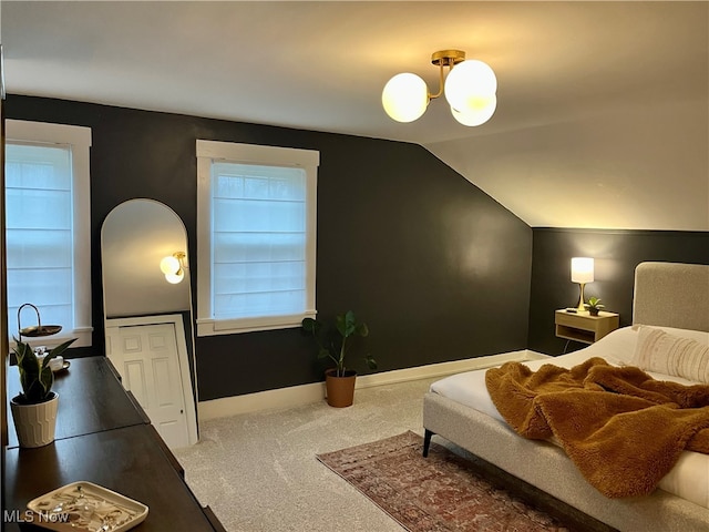 carpeted bedroom with lofted ceiling and an inviting chandelier