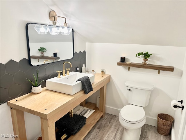 bathroom with hardwood / wood-style floors, lofted ceiling, sink, decorative backsplash, and toilet