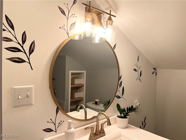 bathroom featuring vanity, toilet, and lofted ceiling