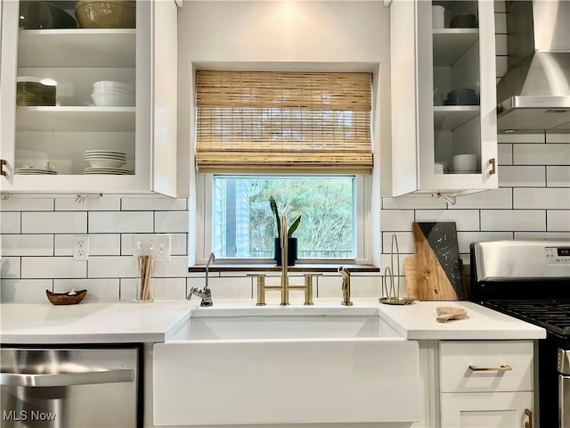 kitchen with decorative backsplash, appliances with stainless steel finishes, white cabinetry, and wall chimney exhaust hood