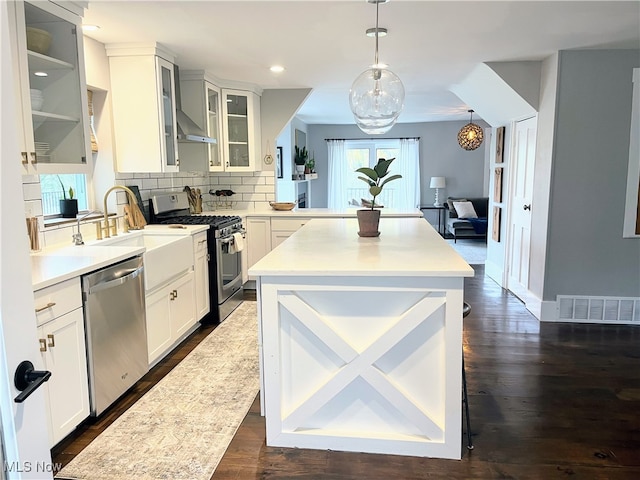 kitchen featuring white cabinets, appliances with stainless steel finishes, decorative light fixtures, and plenty of natural light