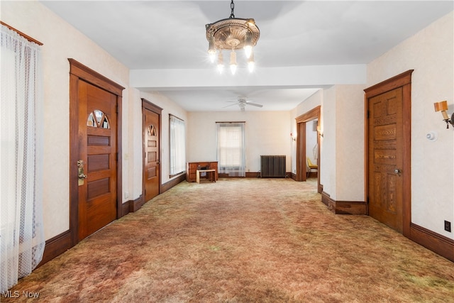 unfurnished room featuring ceiling fan with notable chandelier, radiator heating unit, and carpet floors