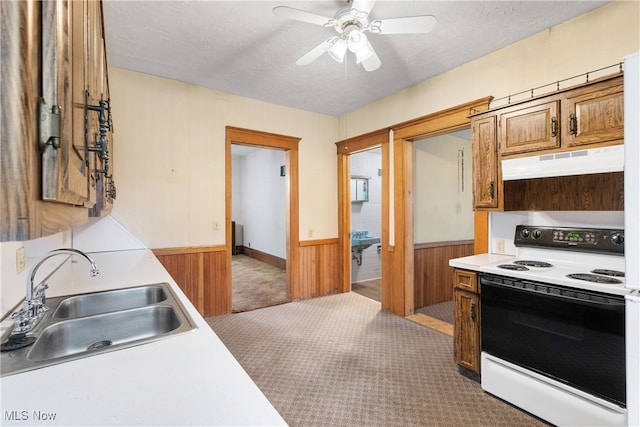 kitchen with light carpet, a textured ceiling, sink, white electric range, and wood walls