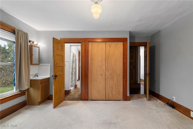 unfurnished bedroom featuring light colored carpet, sink, and a closet