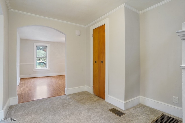 empty room featuring light carpet, visible vents, arched walkways, and ornamental molding