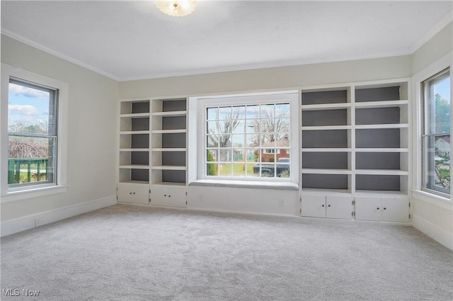 carpeted empty room featuring a healthy amount of sunlight, crown molding, and baseboards