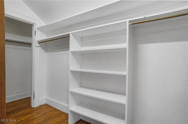 spacious closet featuring lofted ceiling and dark wood finished floors