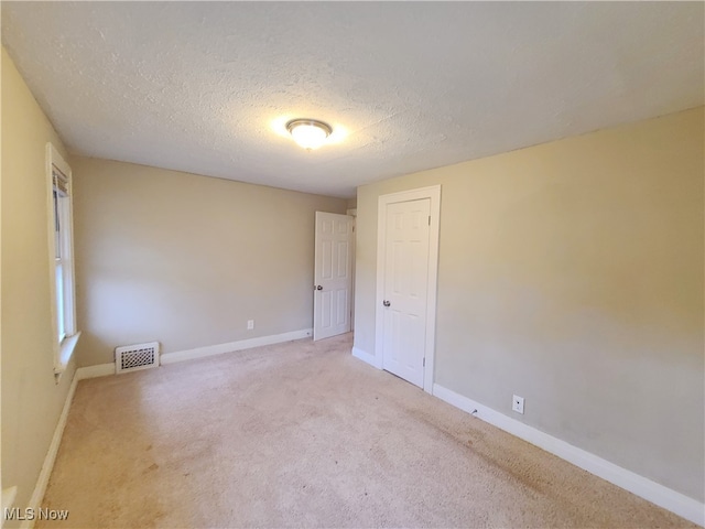 spare room featuring a textured ceiling and light carpet