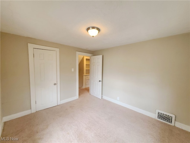 unfurnished bedroom with light carpet and a closet