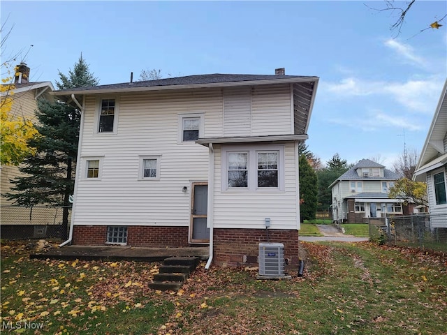 rear view of house featuring central AC and a lawn