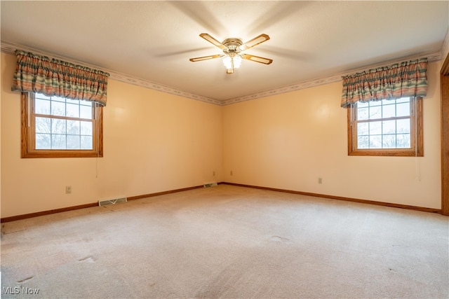 carpeted empty room featuring plenty of natural light, ceiling fan, and crown molding