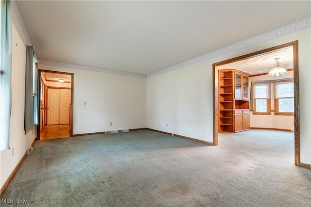 empty room with carpet, an inviting chandelier, and ornamental molding