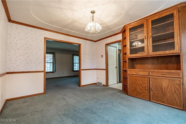 unfurnished dining area with a textured ceiling, crown molding, light carpet, and a chandelier