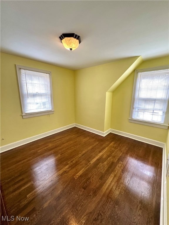 additional living space with dark hardwood / wood-style floors and a healthy amount of sunlight