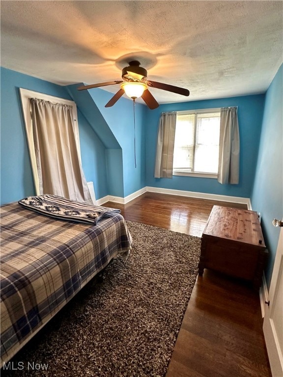 bedroom with ceiling fan, dark hardwood / wood-style flooring, and a textured ceiling