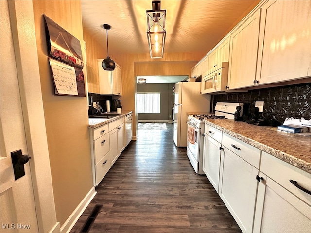 kitchen featuring light stone countertops, backsplash, white appliances, pendant lighting, and dark hardwood / wood-style floors