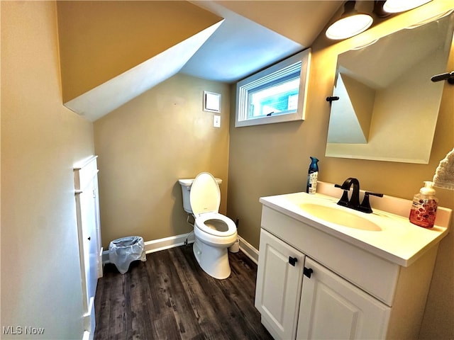 bathroom with toilet, wood-type flooring, vanity, and vaulted ceiling