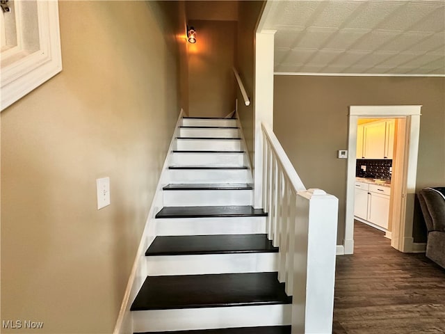 staircase featuring wood-type flooring and crown molding