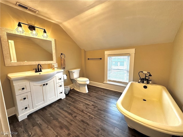 bathroom featuring a bathing tub, vaulted ceiling, toilet, vanity, and hardwood / wood-style flooring