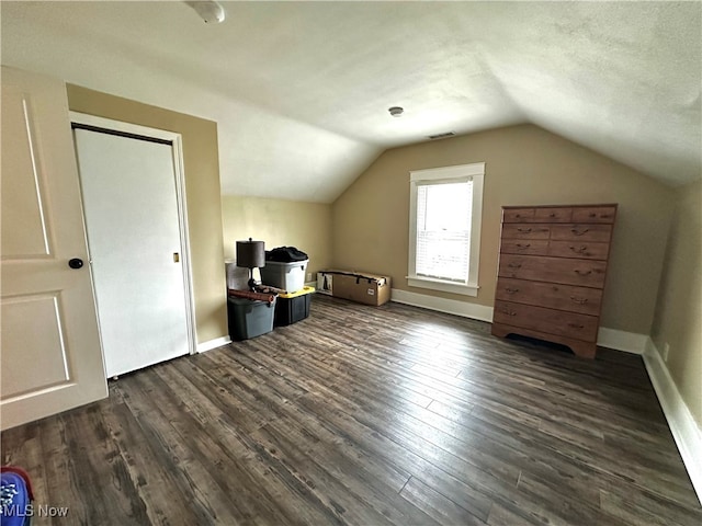 bonus room featuring a textured ceiling, vaulted ceiling, and dark wood-type flooring