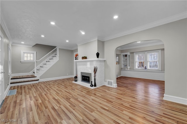 unfurnished living room featuring crown molding, light hardwood / wood-style flooring, and a brick fireplace