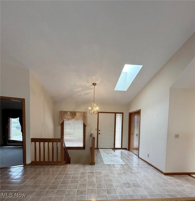 foyer featuring lofted ceiling with skylight, light tile patterned floors, and an inviting chandelier