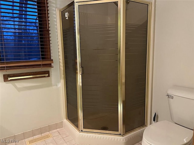 bathroom with toilet, a shower with door, and tile patterned flooring