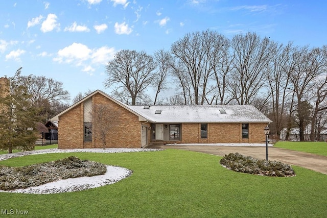 view of front of home featuring a front lawn, brick siding, and curved driveway