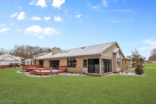 rear view of property featuring a deck, a yard, crawl space, brick siding, and a chimney