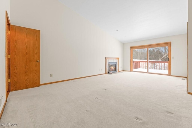 unfurnished living room featuring baseboards, high vaulted ceiling, a fireplace, and carpet flooring