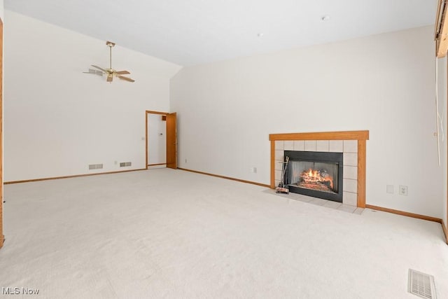 unfurnished living room with a tiled fireplace, visible vents, baseboards, and lofted ceiling