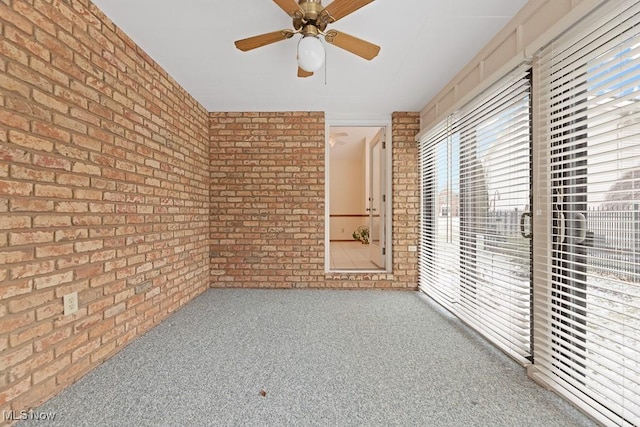 empty room with ceiling fan, carpet floors, and brick wall