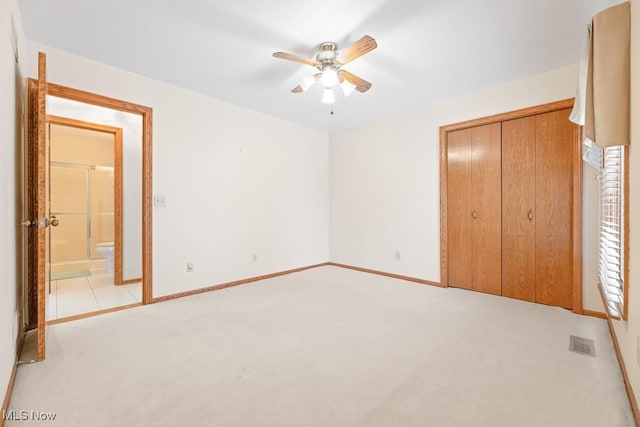 unfurnished bedroom featuring visible vents, baseboards, light carpet, a closet, and a ceiling fan