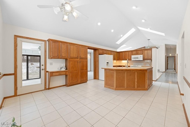 kitchen with light tile patterned floors, vaulted ceiling with skylight, white appliances, and light countertops