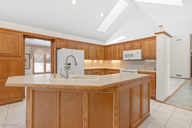 kitchen featuring a large island, white appliances, a skylight, and light countertops