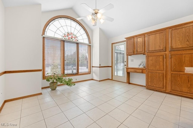 unfurnished dining area featuring baseboards, light tile patterned flooring, a ceiling fan, and vaulted ceiling