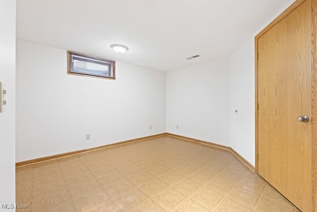 empty room with light floors, visible vents, and baseboards