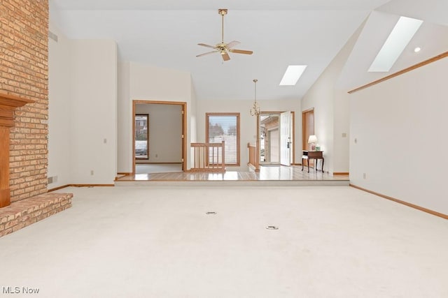 unfurnished living room with high vaulted ceiling, a skylight, baseboards, light colored carpet, and ceiling fan