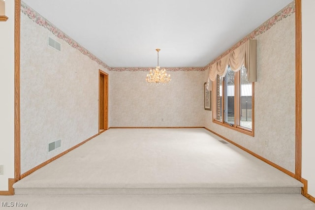 carpeted spare room featuring visible vents, baseboards, an inviting chandelier, and wallpapered walls