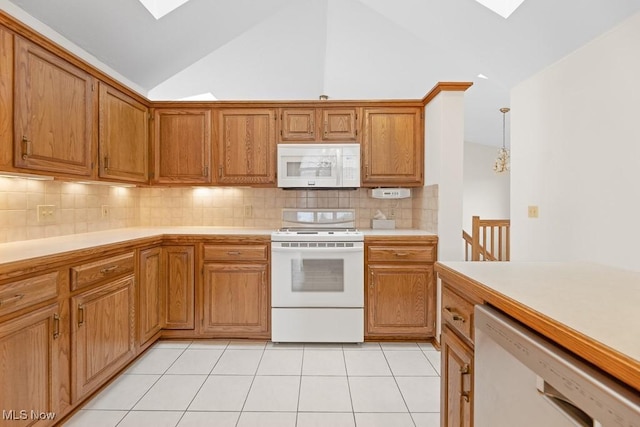 kitchen with light tile patterned flooring, vaulted ceiling with skylight, white appliances, and light countertops