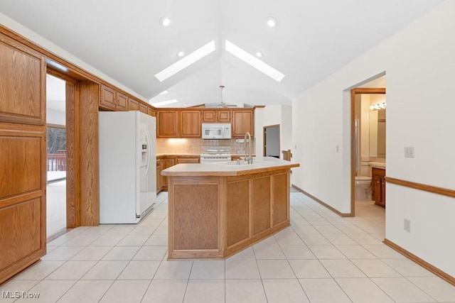 kitchen with white appliances, light tile patterned flooring, a sink, light countertops, and backsplash