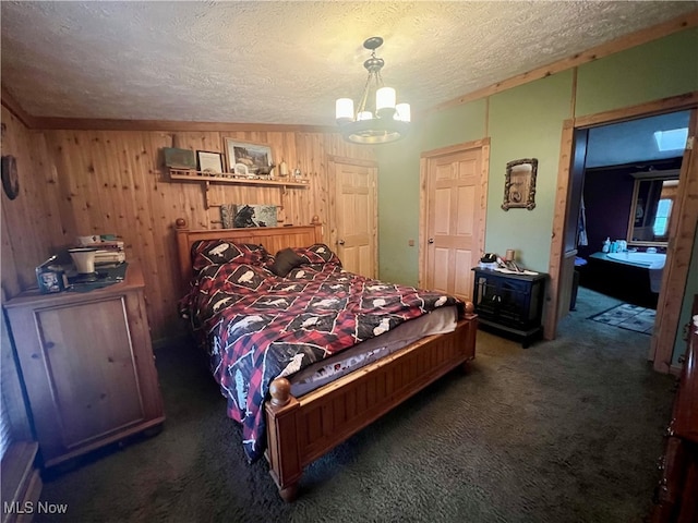 bedroom with a chandelier, wooden walls, dark carpet, and a textured ceiling