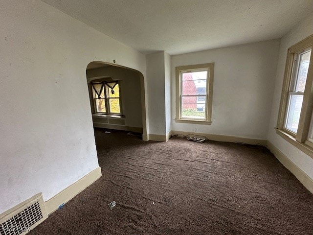 empty room with dark carpet and a textured ceiling