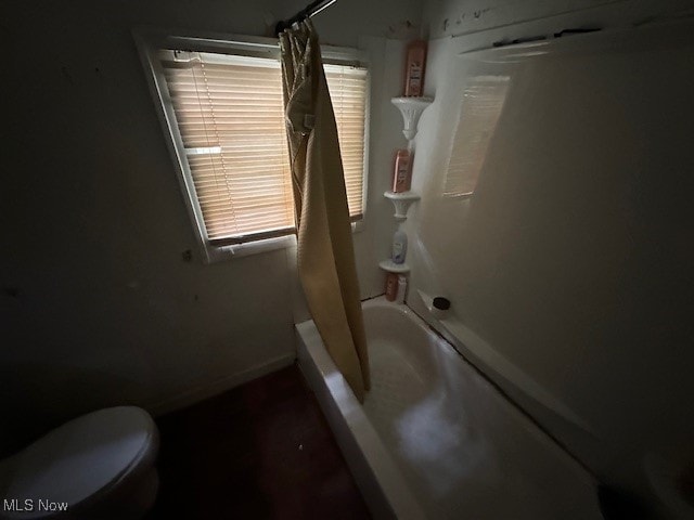 bathroom featuring plenty of natural light, toilet, and shower / bath combo with shower curtain